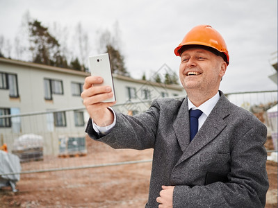 建筑物男工程师自拍穿西装和硬帽做背景建筑工场的地细胞照片图片