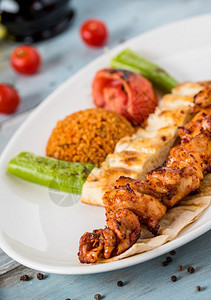炙烤美味的传统土耳其烤鸡肉串和蔬菜在叉子上图片