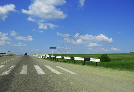 驾驶高加索超过横宽的高速公路和草地云穿越蓝天空图片