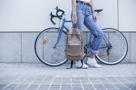 站在自行车旁边手背包的年轻女子图片