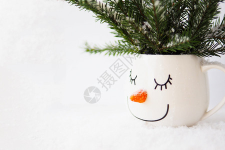 童年乐趣一个杯子里的雪圆枝与一个沉睡雪人的脸相容在白色背景复制空间上睡眠图片