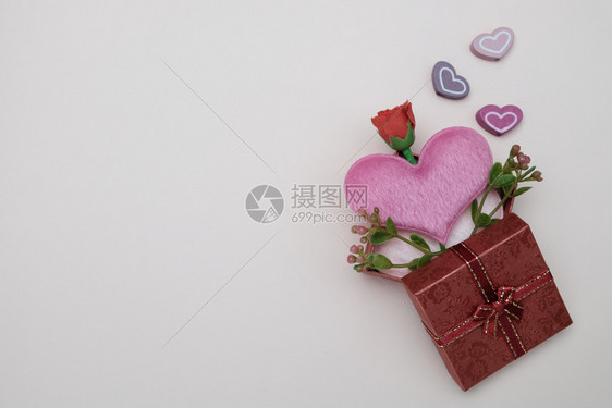 小型的盒子螺柱心形枕头和以粉红背景情人节概念为礼物盒中的小花图片