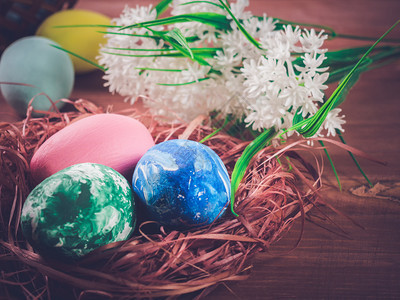 红色的时间假期鸟巢中的复活节鸡蛋和木本底的白花图片