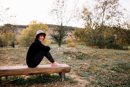 妇女练瑜伽和在公园长椅上伸展帽子冥想季节图片