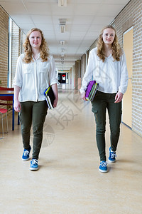 教育青年少两名天主教女孩在长途学校走廊上着带课本的幼女图片