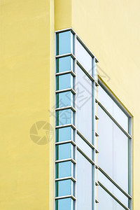 结构体在现代黄色建筑上的蓝玻璃墙垂直框架低角度和视侧图的蓝色玻璃墙几何模式水泥塔图片