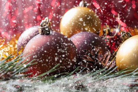 假期白色的冷杉树枝上圣诞球覆盖着雪和飘落的花圣诞球躺在云杉树枝上模糊的背景和飘落雪花玩具图片