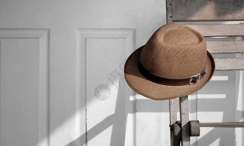 家挂在木椅上的老旧Fedora帽子贴近了日光照着木墙背景表面的影子木头穿图片