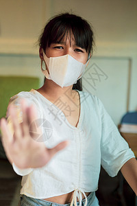 吨年轻的家身戴保护面罩的亚洲青少年用手牌站立不近图片