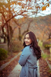 秋天公园年轻亚洲女孩的肖像年轻树叶女图片