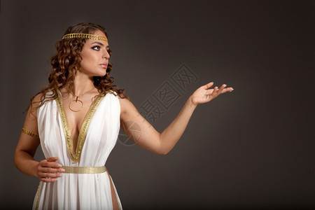 头发美丽的年轻女子穿着白色和金希腊服装在黑暗背景上寻找她左边的东西Y我阿芙罗狄蒂图片