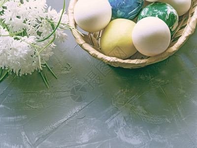 白色的一种春天彩复活节鸡蛋在篮子和深蓝背景的白花朵中图片