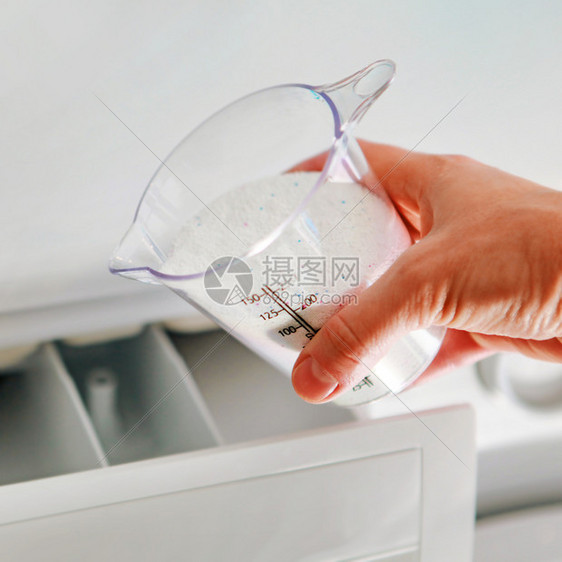 打扫家务加药女人的手填补洗涤机中涂点杯的清洁剂图片