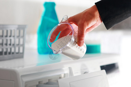 器具女人的手填补洗涤机中涂点杯的清洁剂洗涤自助衣店图片