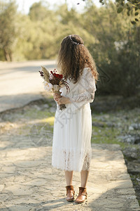 波西米亚风格可爱的新娘和她手上鲜花在户外女孩图片