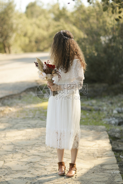 波西米亚风格可爱的新娘和她手上鲜花在户外女孩图片