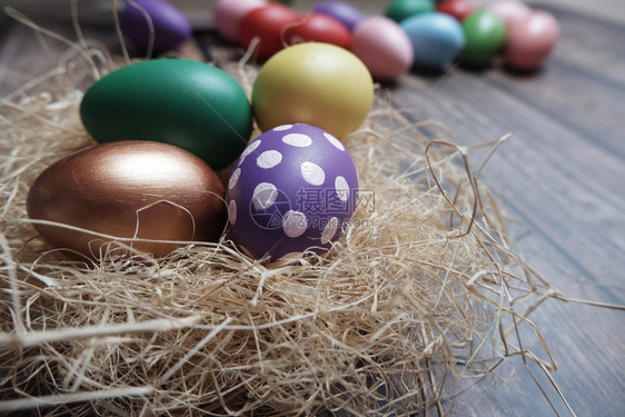 画美丽的关闭木制桌上巢中的彩色复活节鸡蛋假期图片