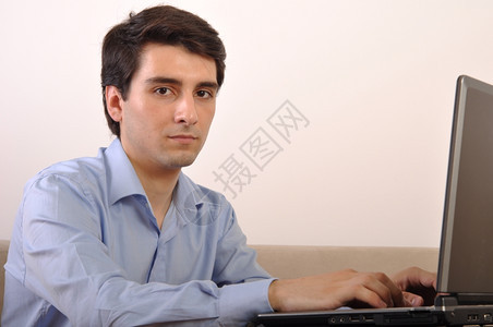在家沙发上坐着膝型电脑的有吸引力年轻人屋在职男图片