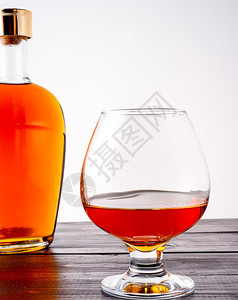 波旁酒一杯白兰地和瓶满的白兰地在木本底的白兰地酒瓶子背景上的白兰地液体木头图片