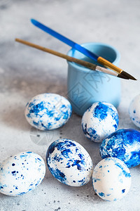 春天有斑点的灰色背景蓝斑点东方鸡蛋配有油漆和刷子装饰鸡蛋为复活节做准备为复活节丰富多彩的图片