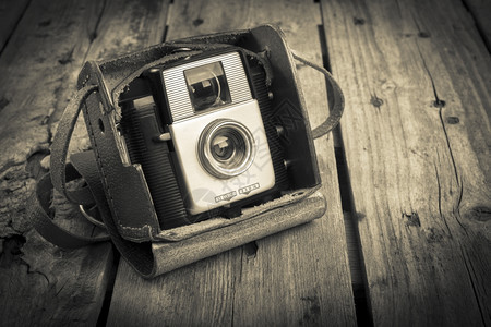 垃圾摇滚原来的旧皮革案相机在木制背景过滤器上被电影图片