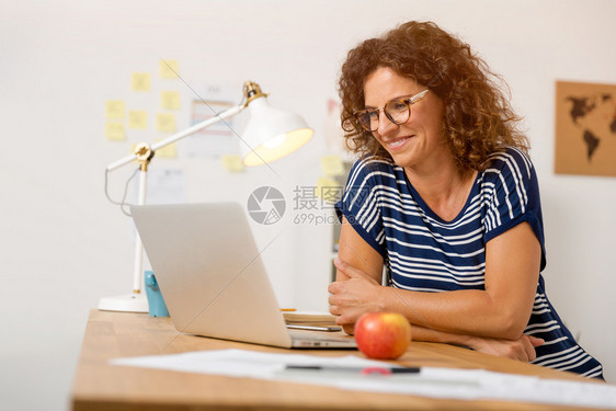 在职的办公室使用笔记本电脑的中年妇女间商业图片