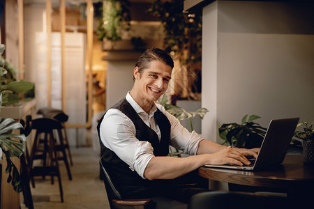 在创意工作空间或咖啡厅从事计算机笔记本电脑工作的笑脸商人在职线办公室图片