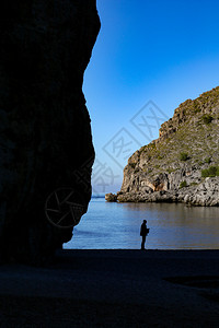 边缘男人等待在海边的地平面与岩石相邻背景图片