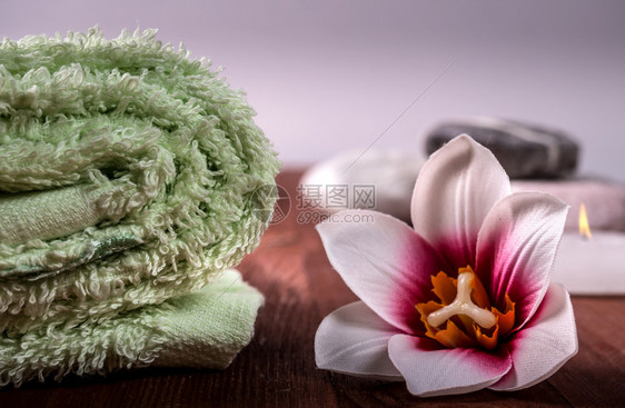 松弛人们美丽卷起的绿色毛巾树上的兰花和背景中石头毛巾背景中的鲜花和石头温泉背景图片