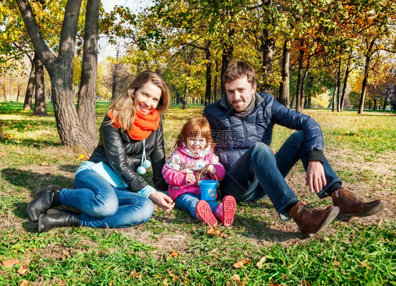 秋天公园中快乐的年轻家庭父母女孩子图片
