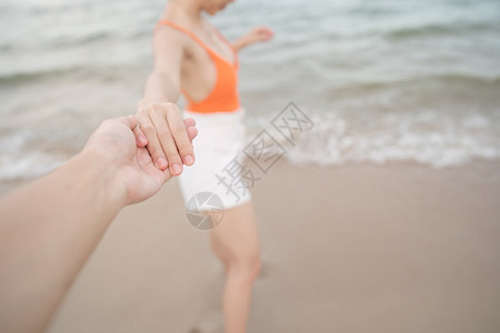 户外女人牵着男朋友的手在海滩上一起跑来去人们自然图片