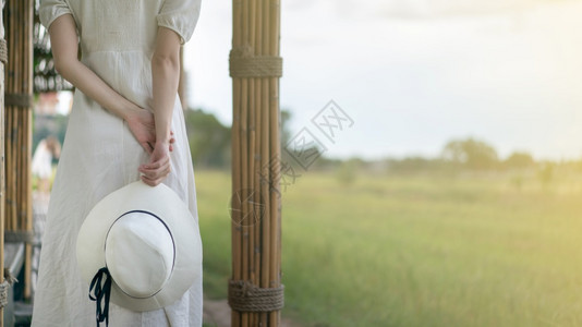 身着白裙子的女在竹布隧道和桥上行走作为穿过稻田的步行道路公园美丽的走道图片