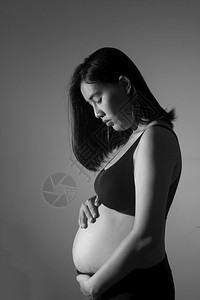 产假怀孕7个月白发黑的孕妇站着并抱她的肚子家母体图片