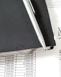 写金融带有财务表格和文件的上一张黑纸条的银笔面有财务表格和单据财务表格注纸和桌子上的笔黑色图片