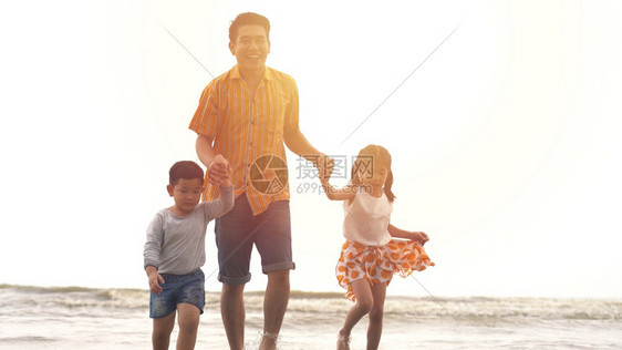 爸爸带着儿子和女儿在沙滩上玩耍图片