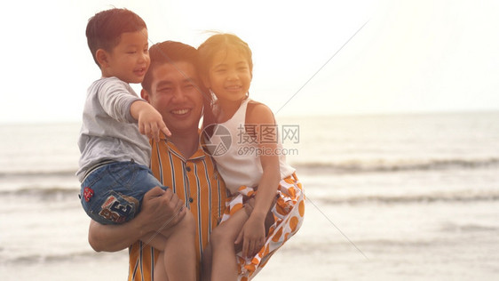 爸爸带着儿子和女儿在沙滩上玩耍图片