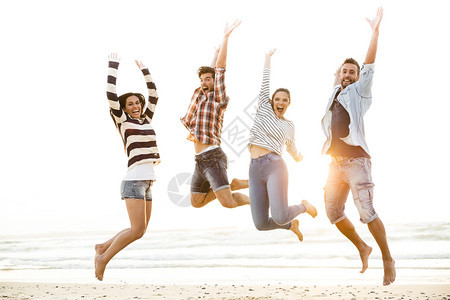 朋友在沙滩上一起跳跃图片