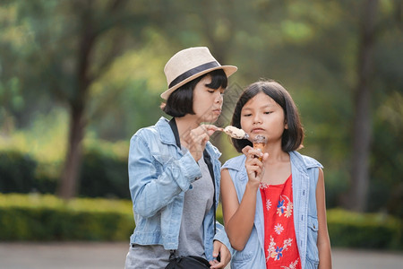 食物白种人们两个女孩在公园散步时街上吃冰淇淋图片