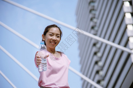 苗条的楼上自然女在运动后饮用现代城市的矿泉水在年轻女户外锻炼时身穿健康运动服并超越健康生活方式的女概念在健康生活方式之外进行户锻图片