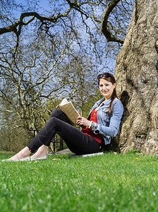 娱乐一名年轻女学生在树下习的照片该名青年女学生在树丛下习读阅图片