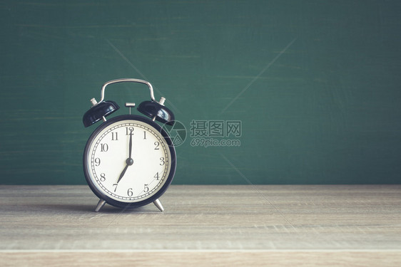 书教室黑板背景的木桌上闹钟回学校概念在课堂上以黑板为背景的木桌敲响闹钟在家工作棕色的图片