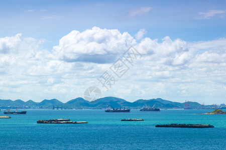 海洋航运明亮的岛上附近海域货船白天明亮空中飘浮着背景图片