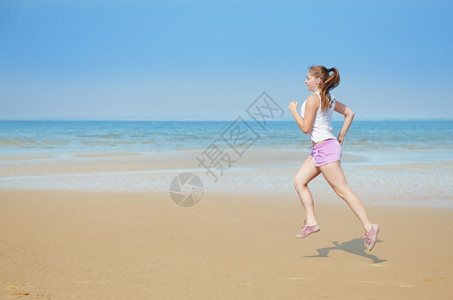银行支撑娱乐迷人的年轻女子独自在海滩上奔跑图片