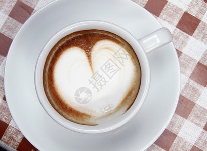 一杯咖啡在白色碗中的心脏模式在彩色背景的白碗中咖啡因屋卡布奇诺图片
