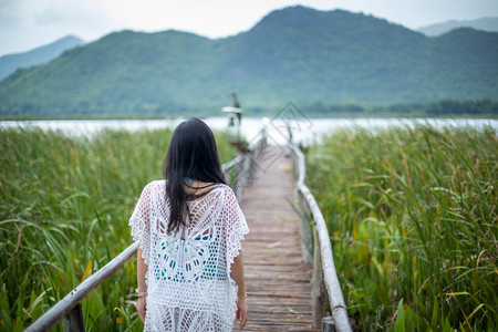 人行道快乐的年轻女站在木桥上以自然背景为本女孩图片