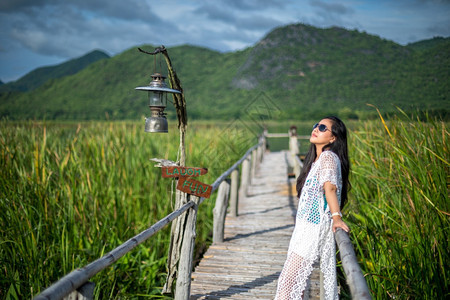 海滩亚洲人年轻女站在木桥上以自然背景为本图片