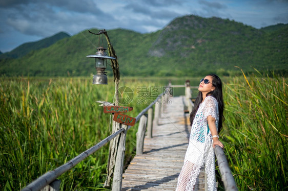 海滩亚洲人年轻女站在木桥上以自然背景为本图片