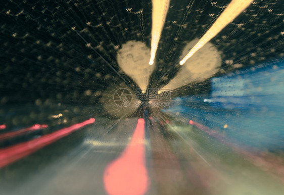 水散景驾驶挡风屏布基和交通灯的闪亮夜雨滴与反向过滤效果模糊的移动缩放背景图片