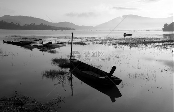 冷清晨宁静的湖以黑黄白色音调渔民在那里生活船只在地表水上反射平的冷静图片