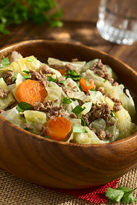 Savoycobbage胡萝卜土豆和小熟食炖菜或木碗里有面食的浓汤用天然光照在暗木上拍摄肉饮食烹饪图片